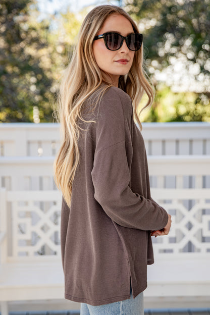 Woman wearing a brown cardigan and sunglasses outdoors