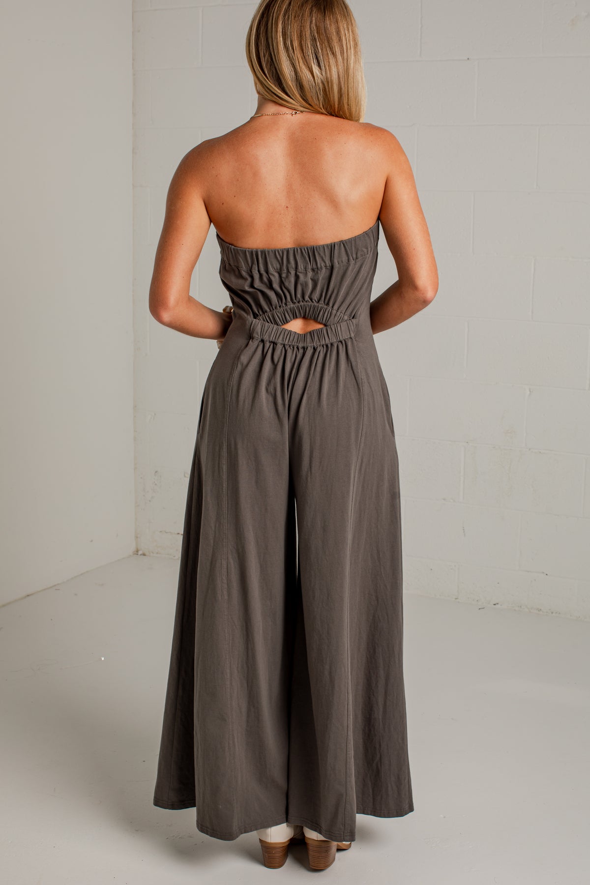 A dark gray strapless wide-leg jumpsuit with side pockets