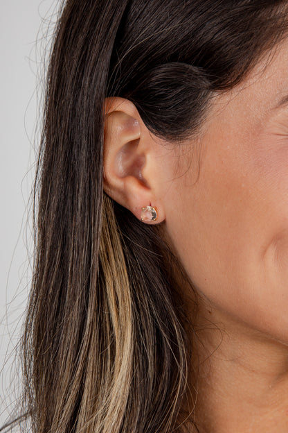 Close-up of an ear with a gold earring against a neutral background