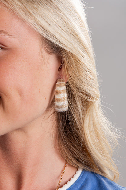 Close-up of a woman wearing striped earrings with a neutral background