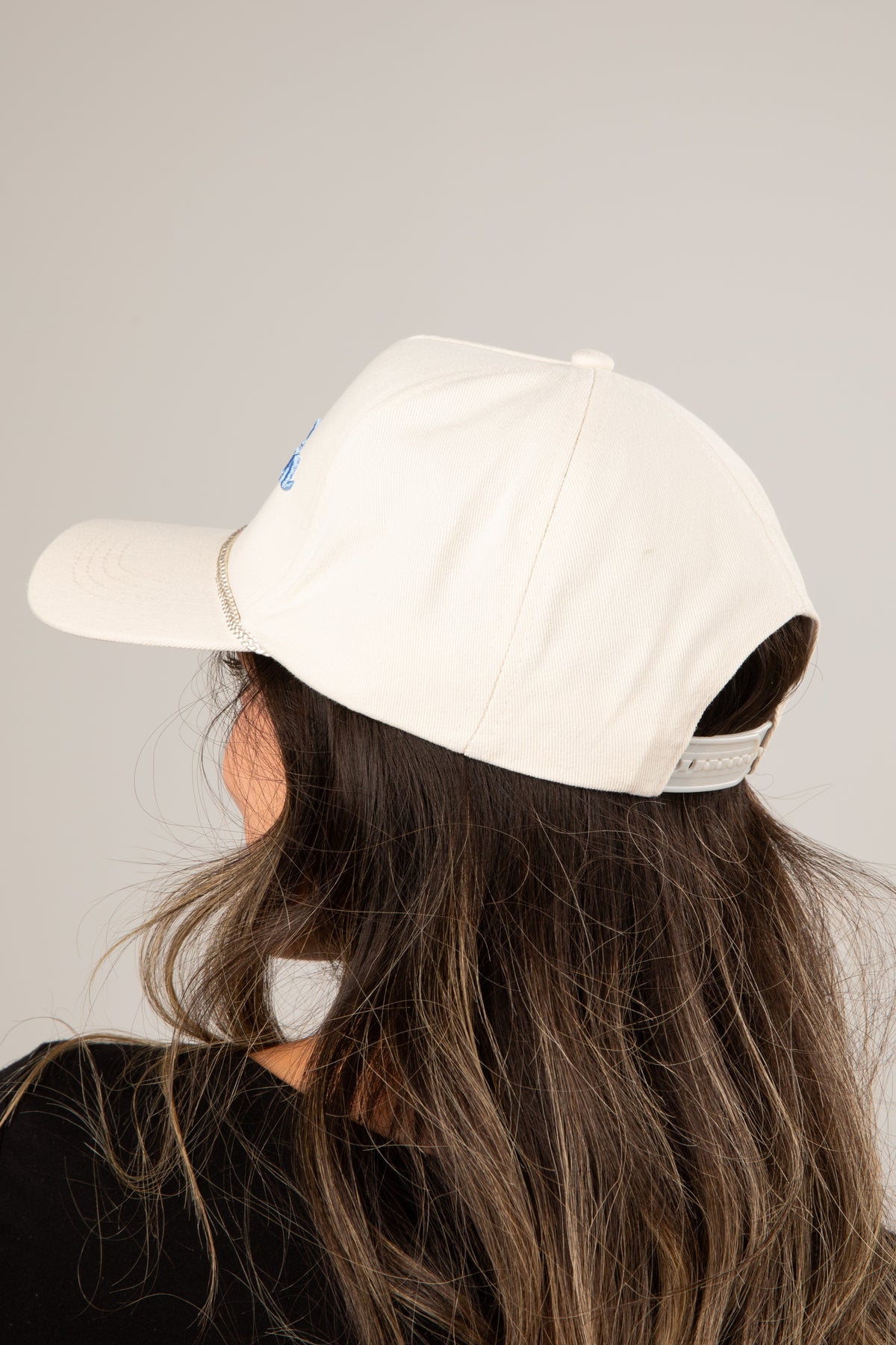 Person wearing a white baseball cap on a plain background