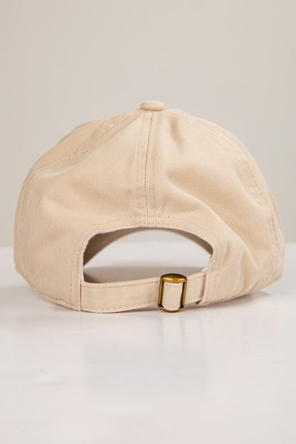 Beige cap with a gold buckle on a light gray background
