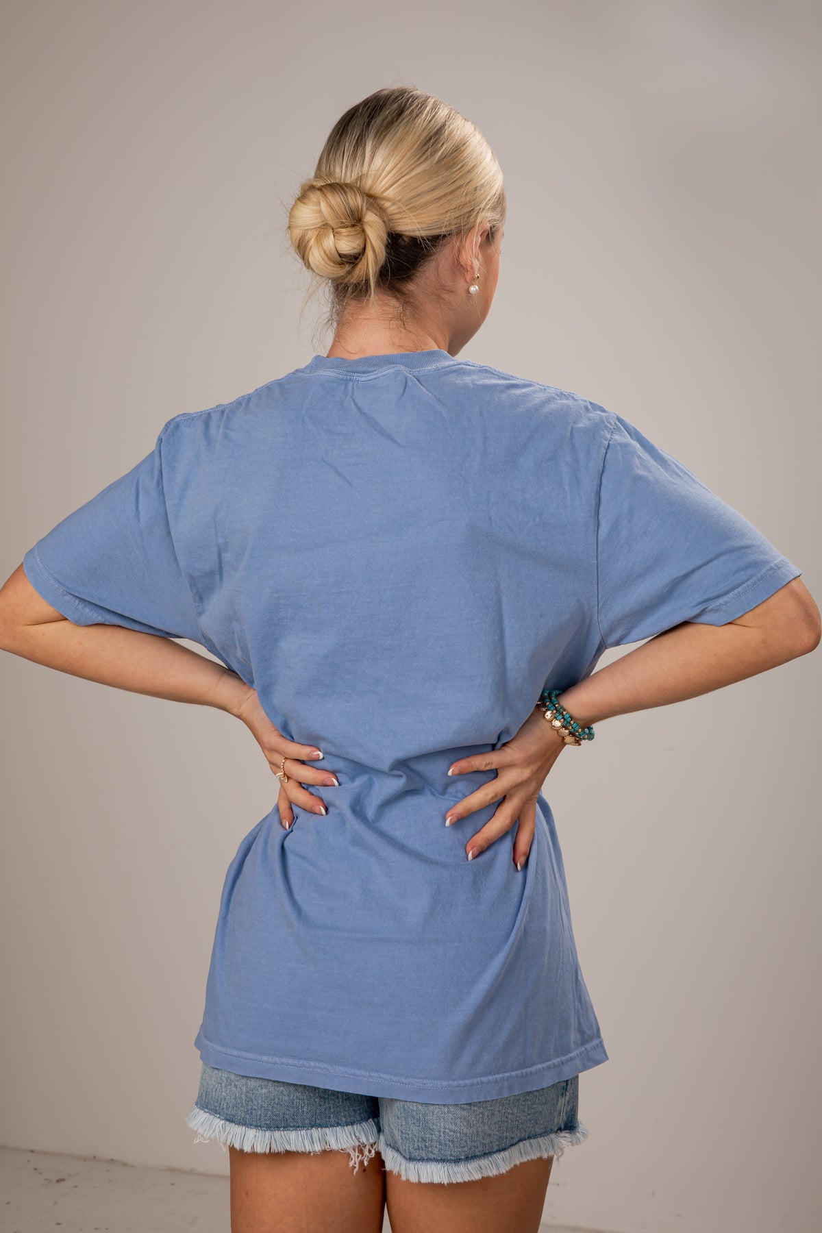 Person wearing a blue t-shirt and denim shorts against a plain background