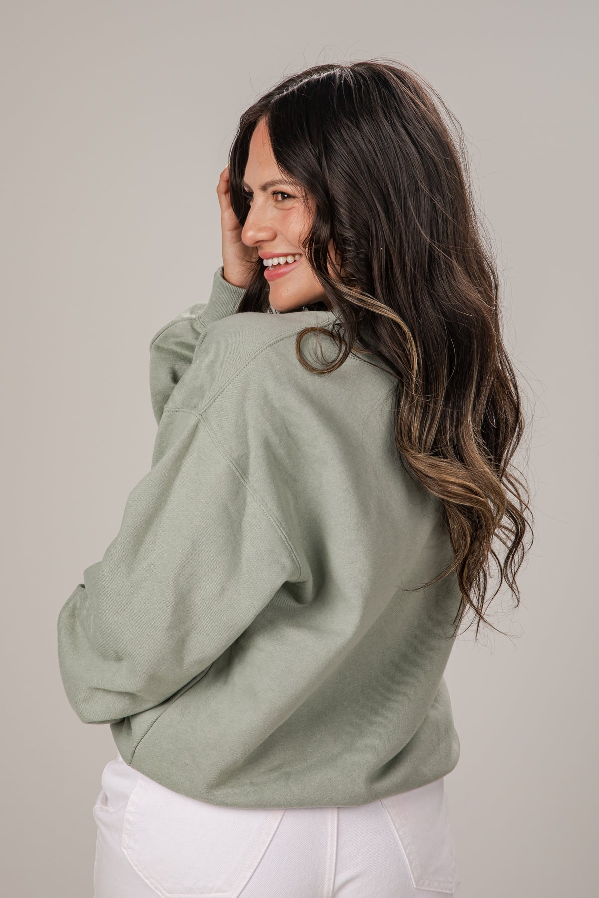 Woman wearing a green sweater against a plain background