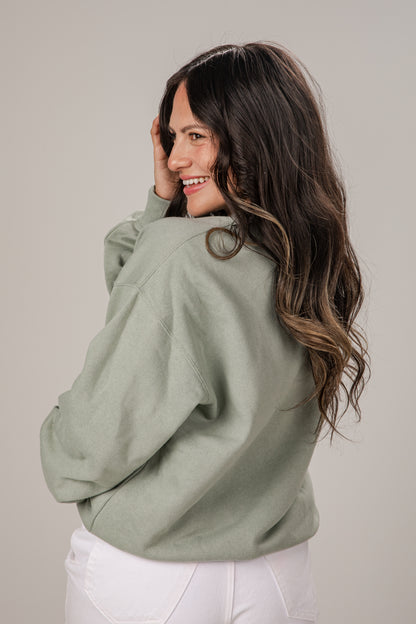 Woman wearing a green sweater against a plain background