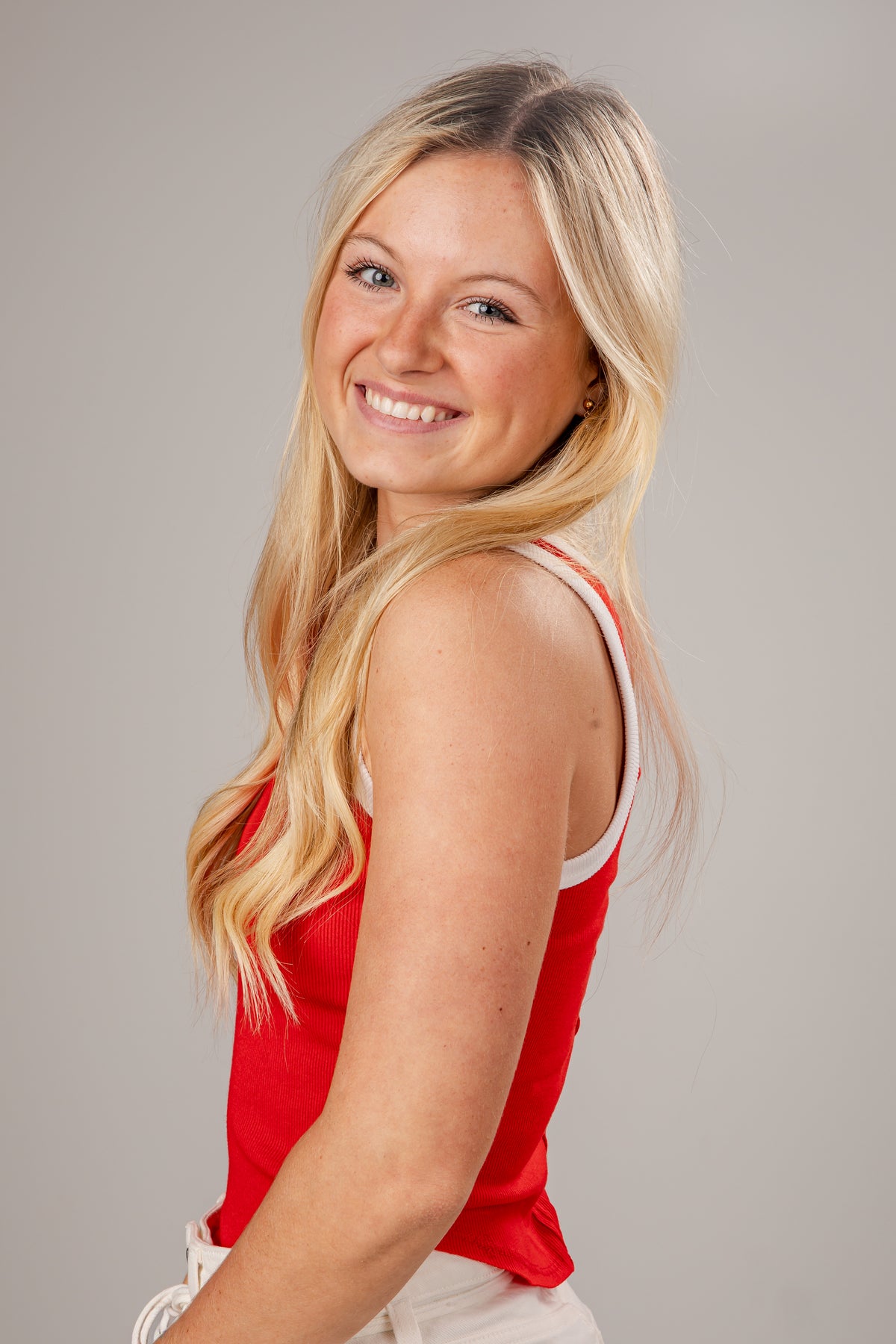 Woman wearing a red tank top against a gray background