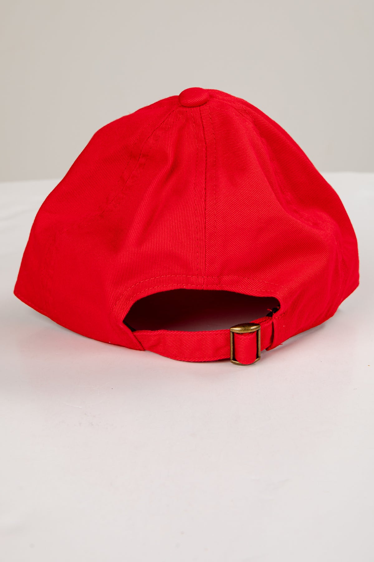 Red cap with a gold buckle on a light gray background
