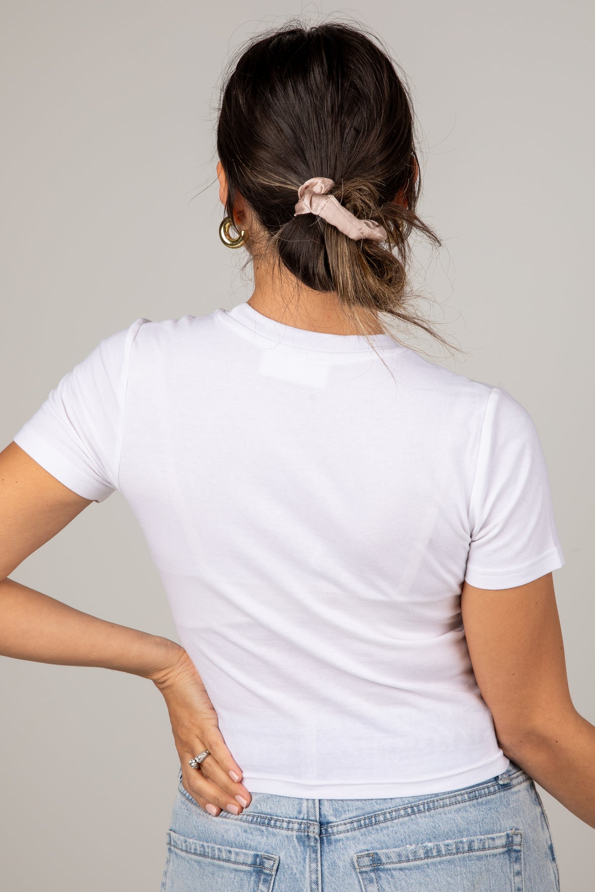 Person wearing a white t-shirt and blue jeans with a neutral background