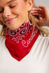 A close-up of a woman wearing a red bandana with a white and black paisley pattern and the word &