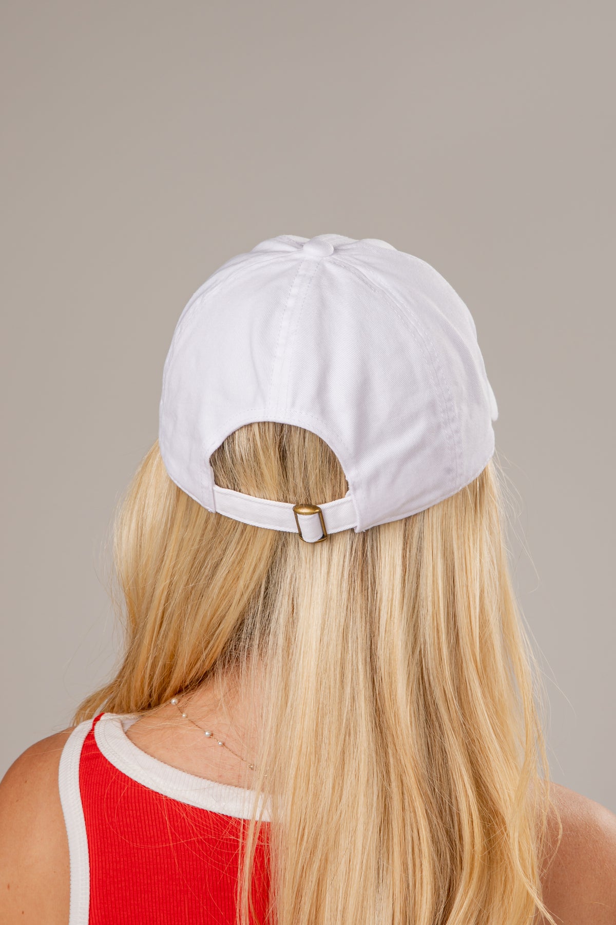 Person wearing a white cap with a beige background