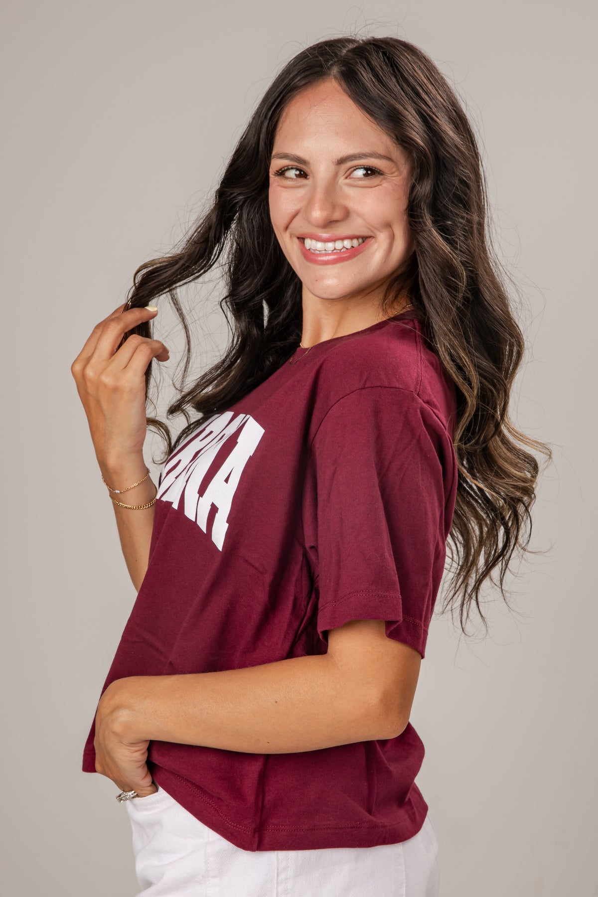 Woman wearing a maroon t-shirt with text on a plain background