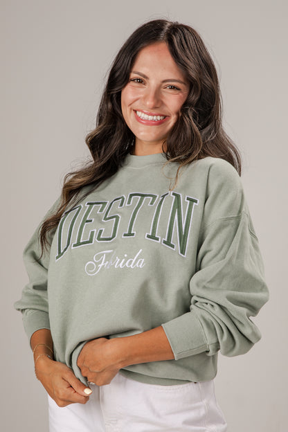 Woman wearing a light green sweatshirt with &