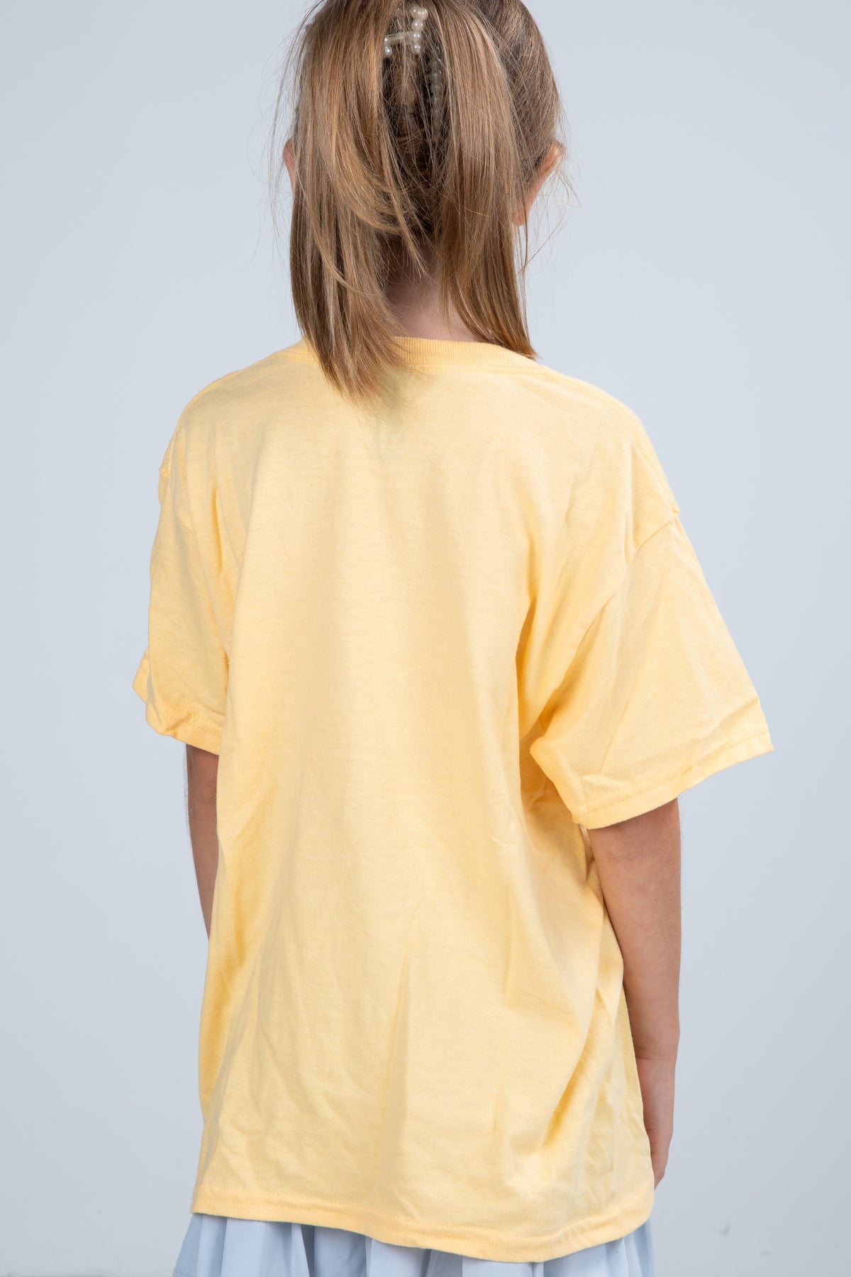Person wearing a yellow t-shirt on a plain background