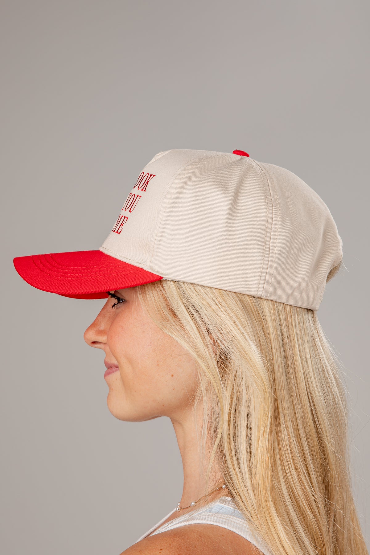 Woman wearing a beige and red cap on a gray background