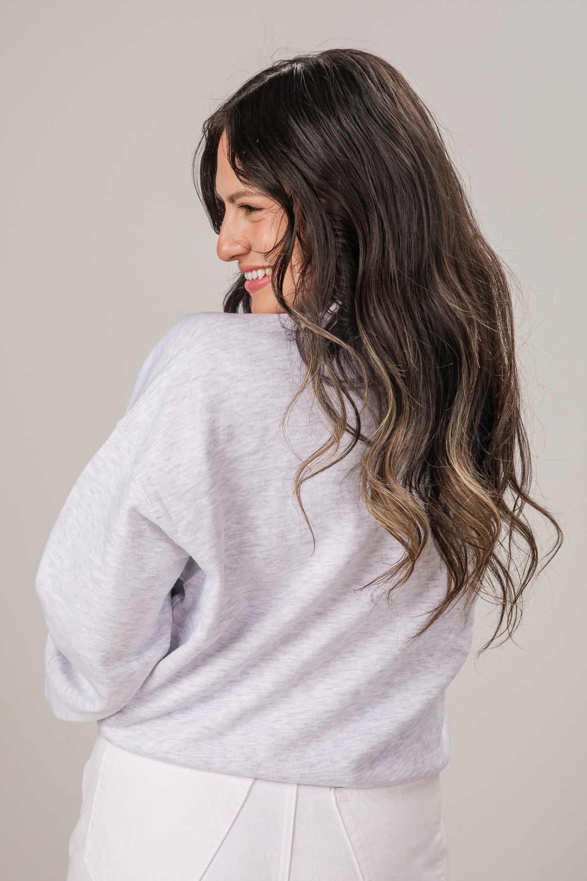 Woman wearing a light gray sweater against a plain background