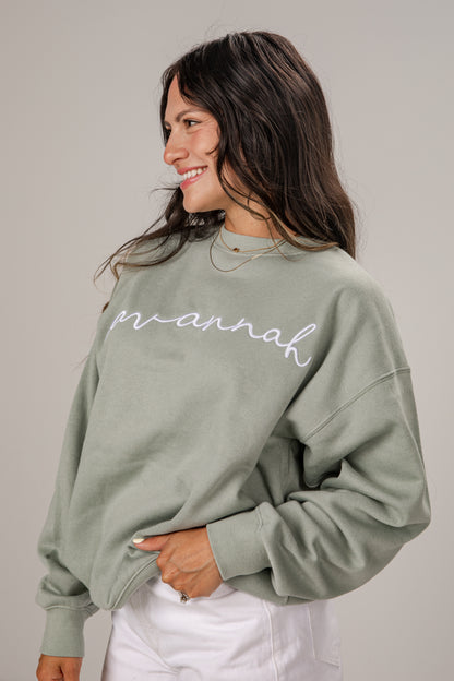 Woman wearing a green sweatshirt with &