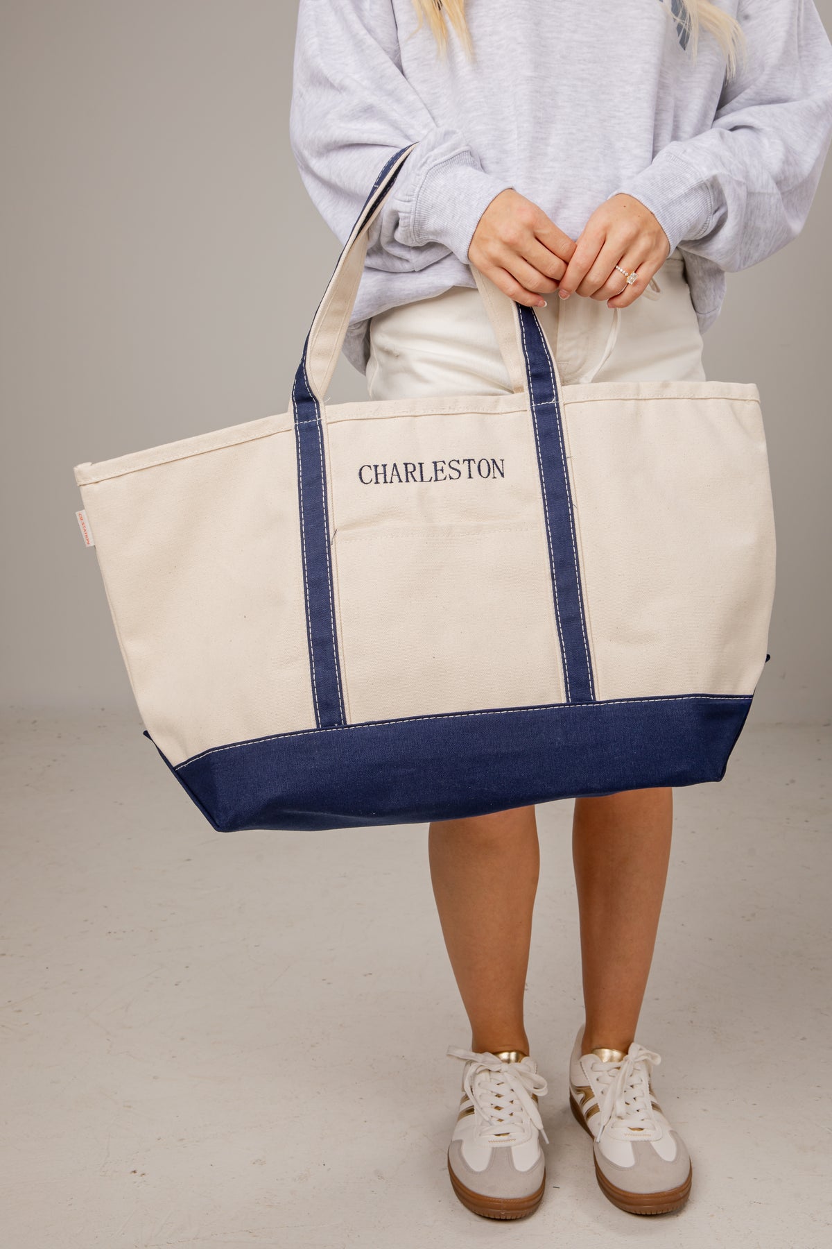 Person holding a white tote bag with blue accents and &