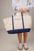 Person holding a white tote bag with blue accents and &