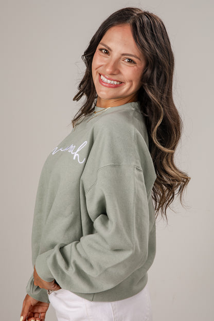 Woman wearing a green sweatshirt with text on a plain background