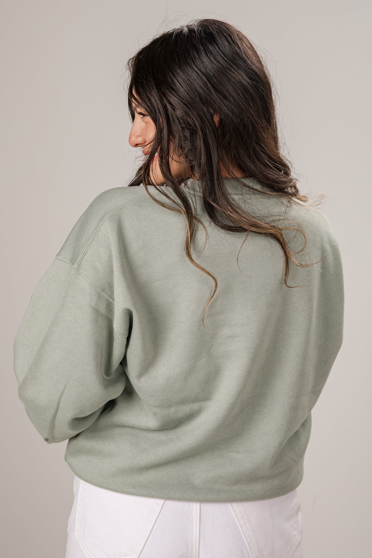 Woman wearing a light green sweater against a plain background