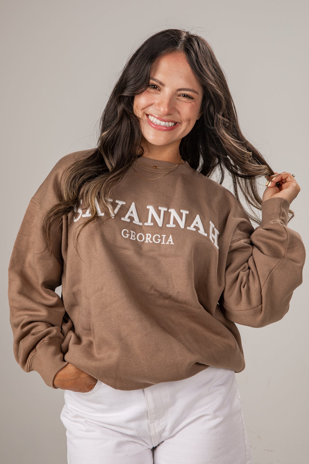 Woman wearing a brown sweatshirt with &