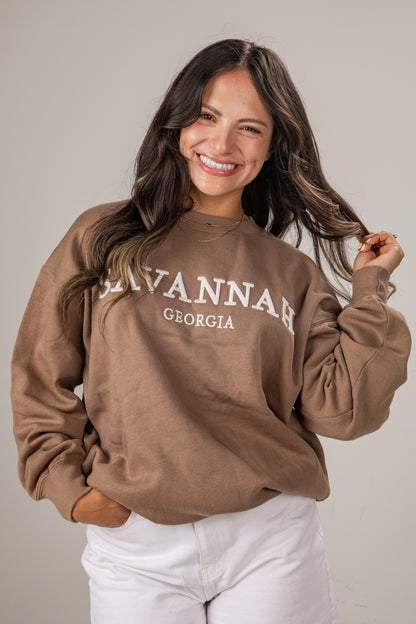 Woman wearing a brown sweatshirt with &