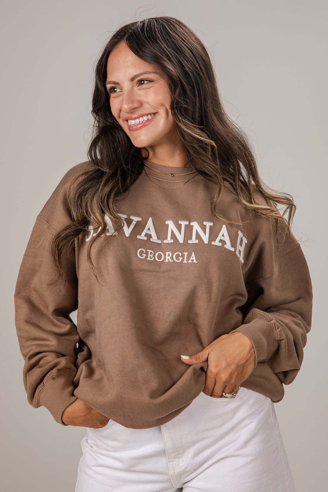 Woman wearing a brown sweatshirt with &