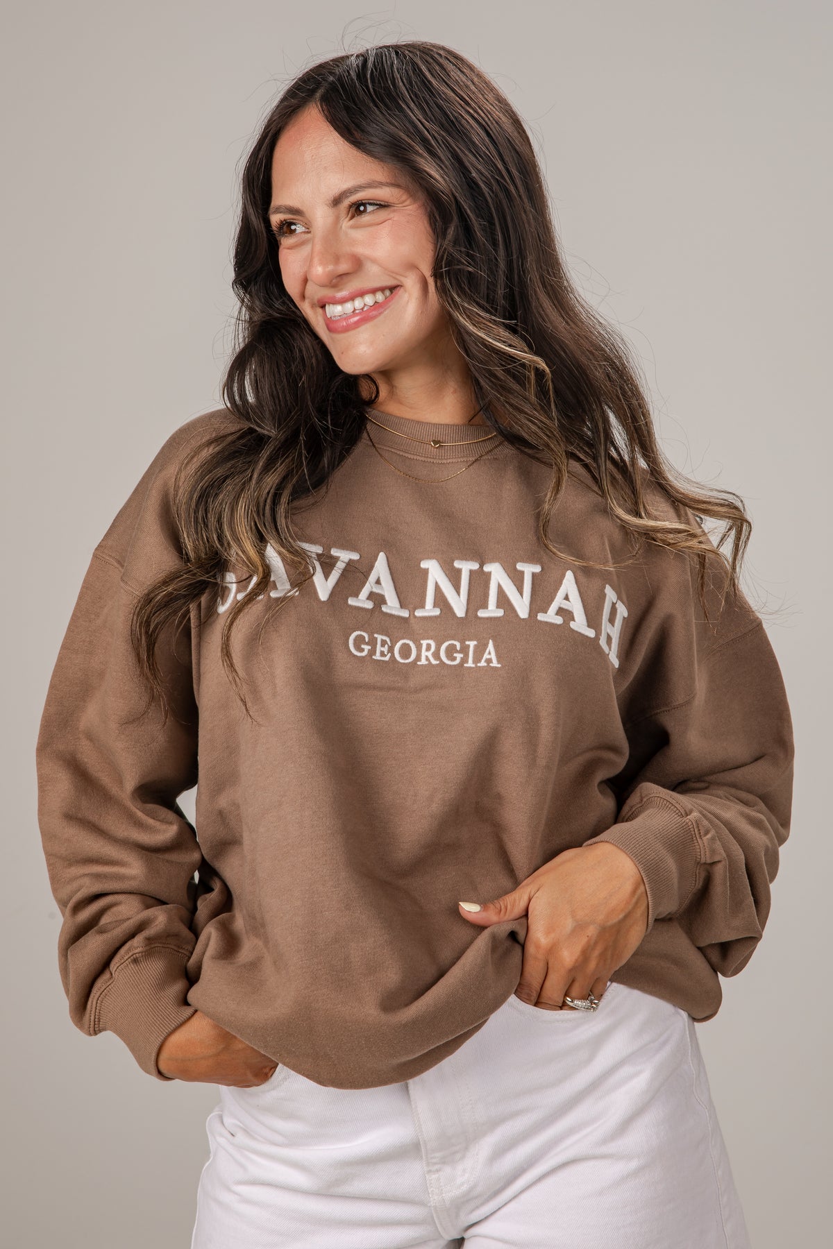 Woman wearing a brown sweatshirt with &