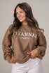 Woman wearing a brown sweatshirt with &