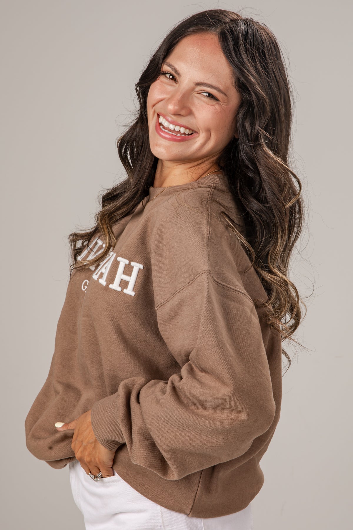 Woman wearing a brown sweatshirt with &