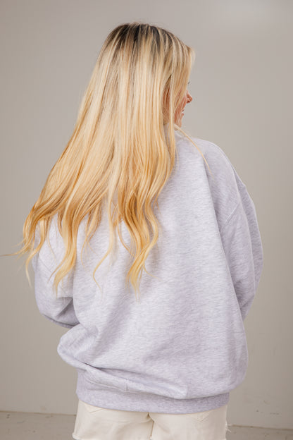 Person wearing a gray mockneck sweatshirt from behind with a neutral background