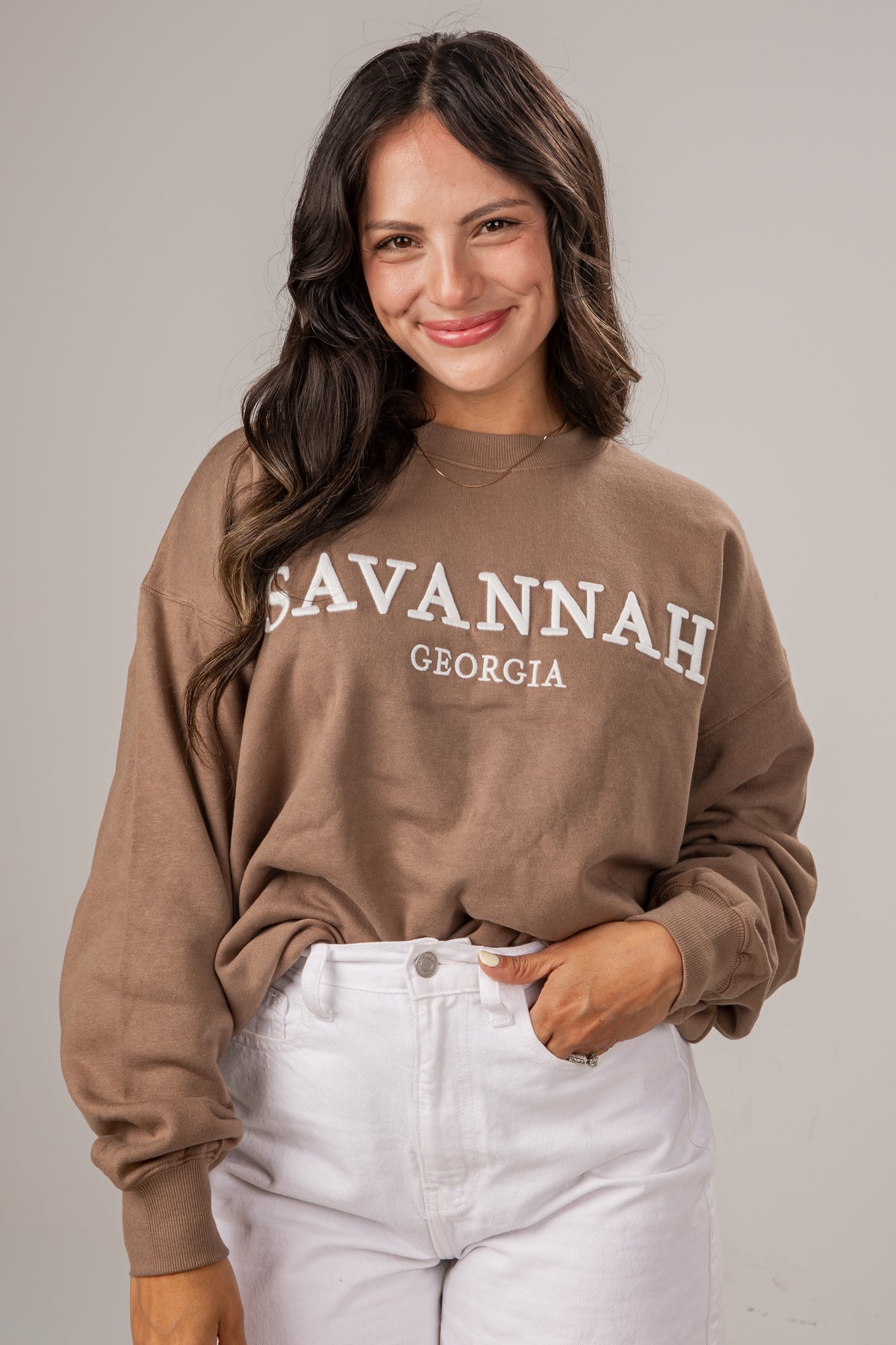 Woman wearing a brown sweatshirt with &