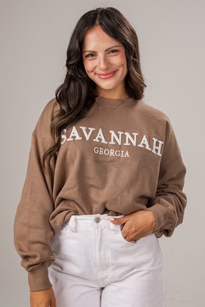 Woman wearing a brown sweatshirt with &