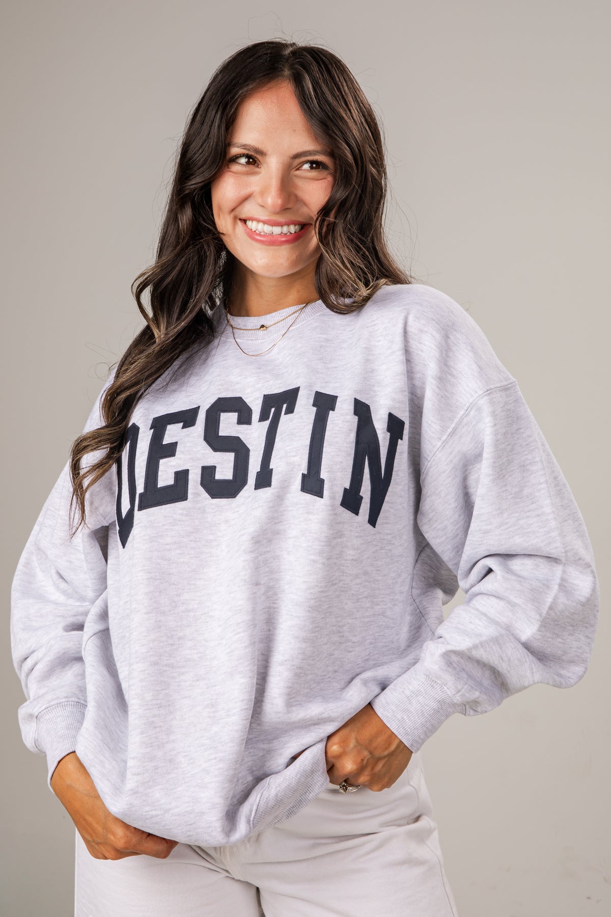 Woman wearing a gray sweatshirt with &