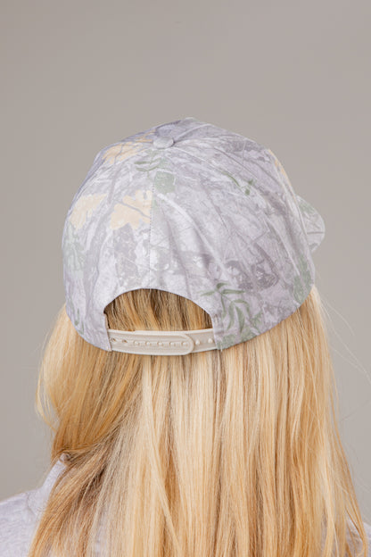 Person wearing a floral-patterned cap on a plain background