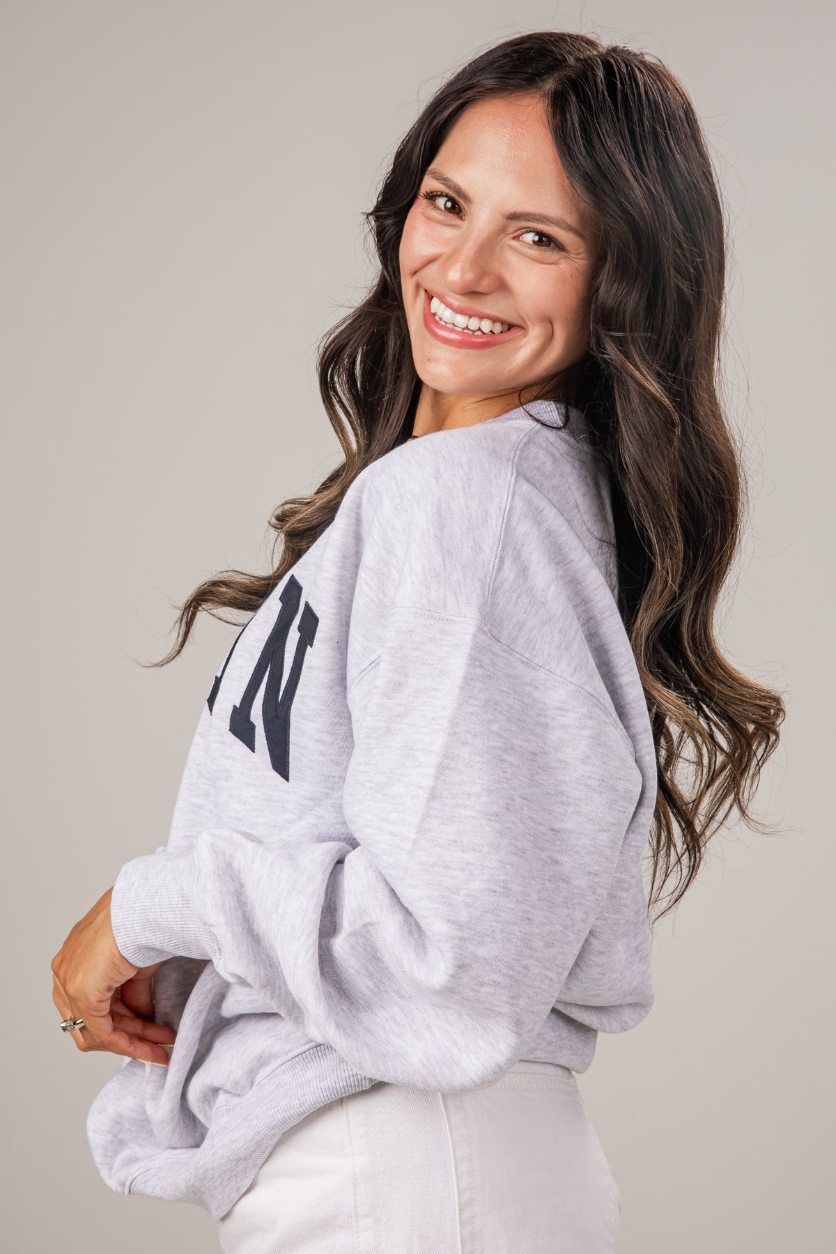 Woman wearing a gray sweatshirt with text on a plain background