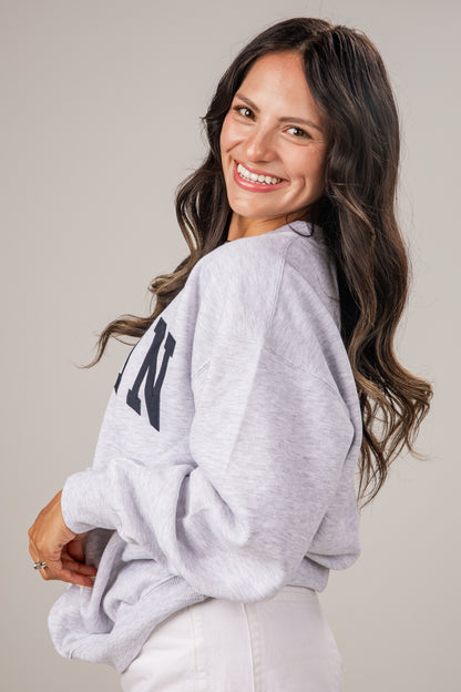 Woman wearing a gray sweatshirt with text on a plain background