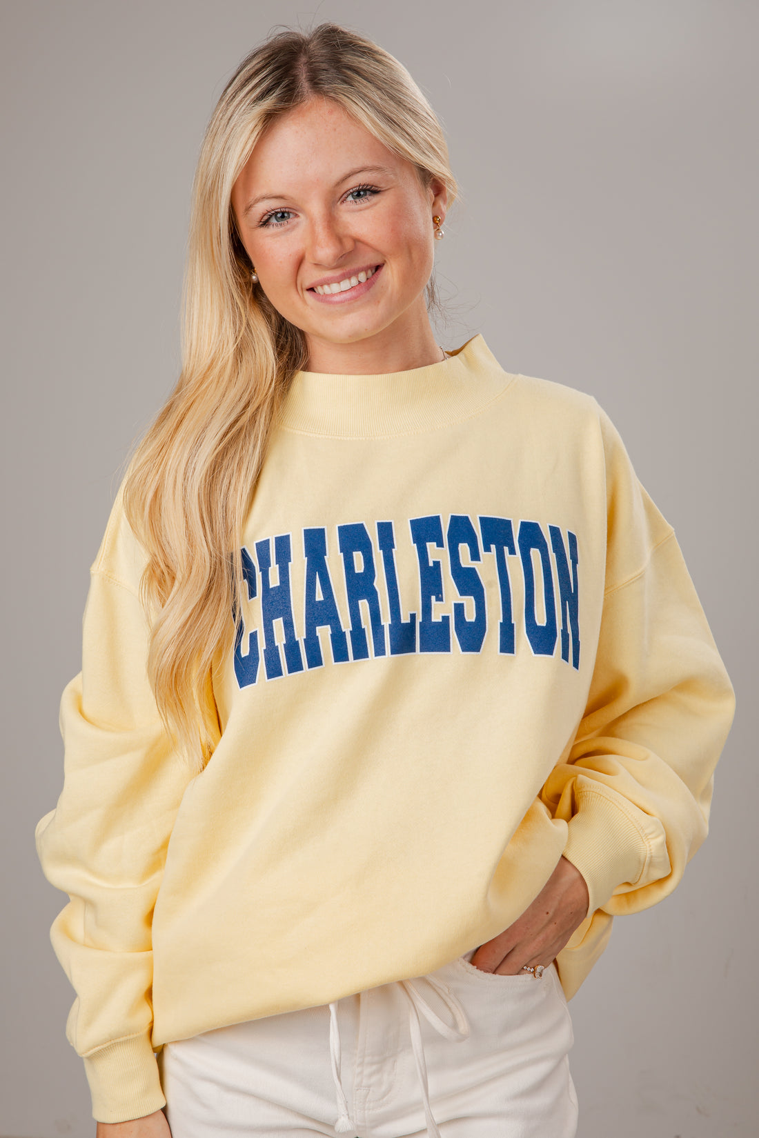 Woman wearing a yellow mocneck sweatshirt with &
