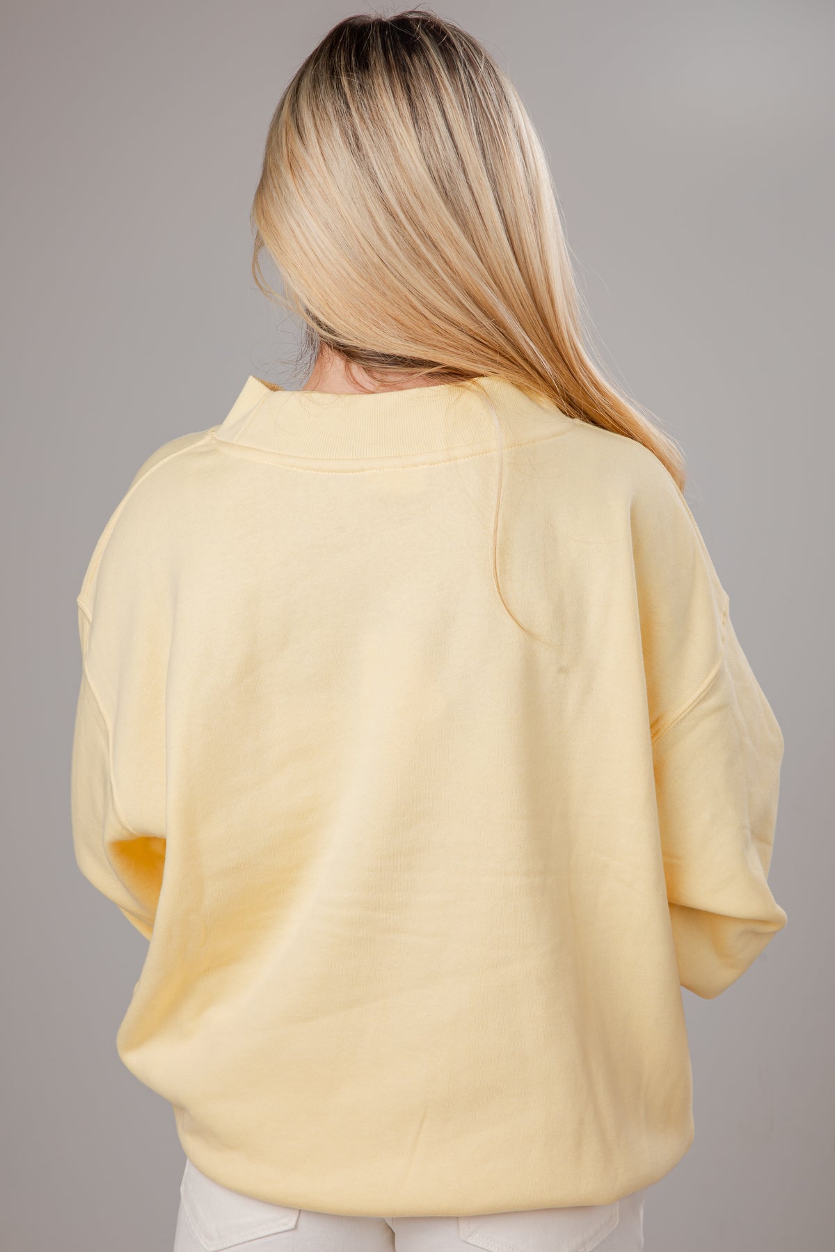 Person wearing a light yellow sweater against a gray background