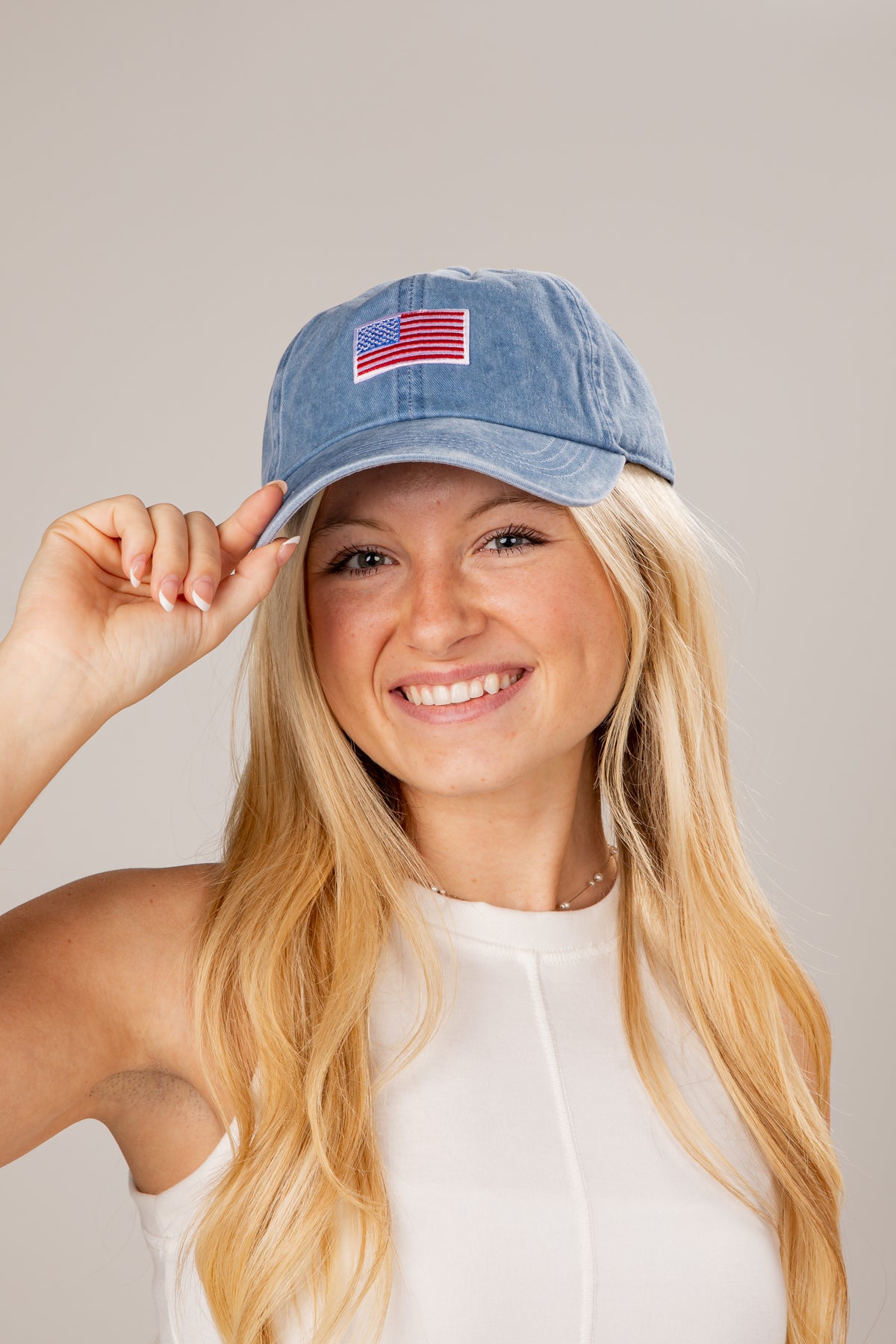 Woman wearing a blue cap with an American flag patch on a plain background