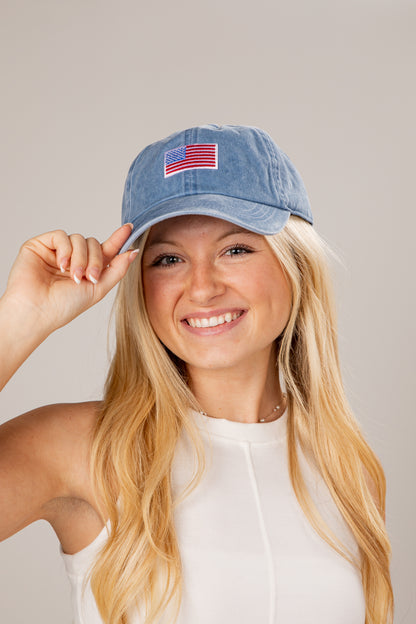 Woman wearing a blue cap with an American flag patch on a plain background