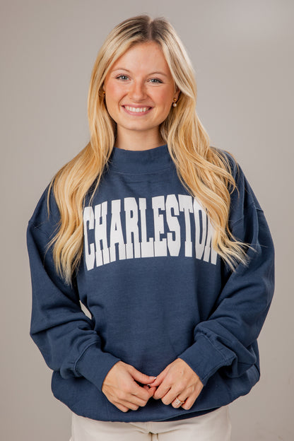 Woman wearing a navy blue mockneck sweatshirt with &