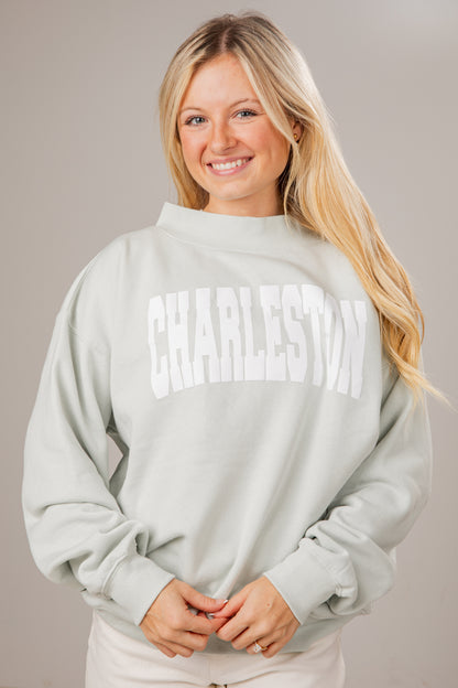 Woman wearing a light gray sweatshirt with &