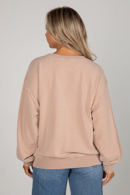 Person wearing a beige sweatshirt and blue jeans on a plain background