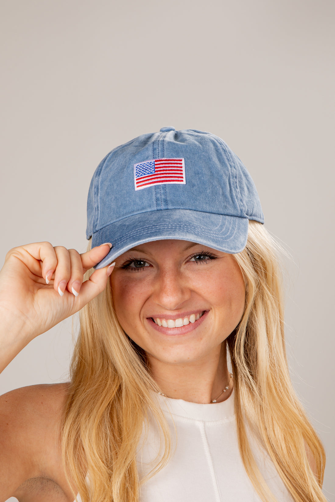 Woman wearing a blue denim cap with an American flag patch on a plain background