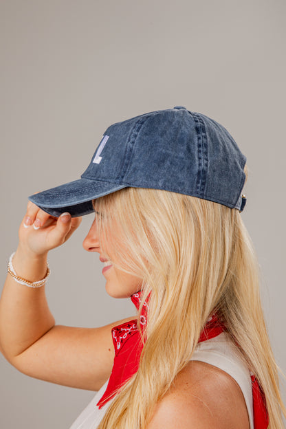 Woman wearing a blue denim cap and red bandana on a plain background