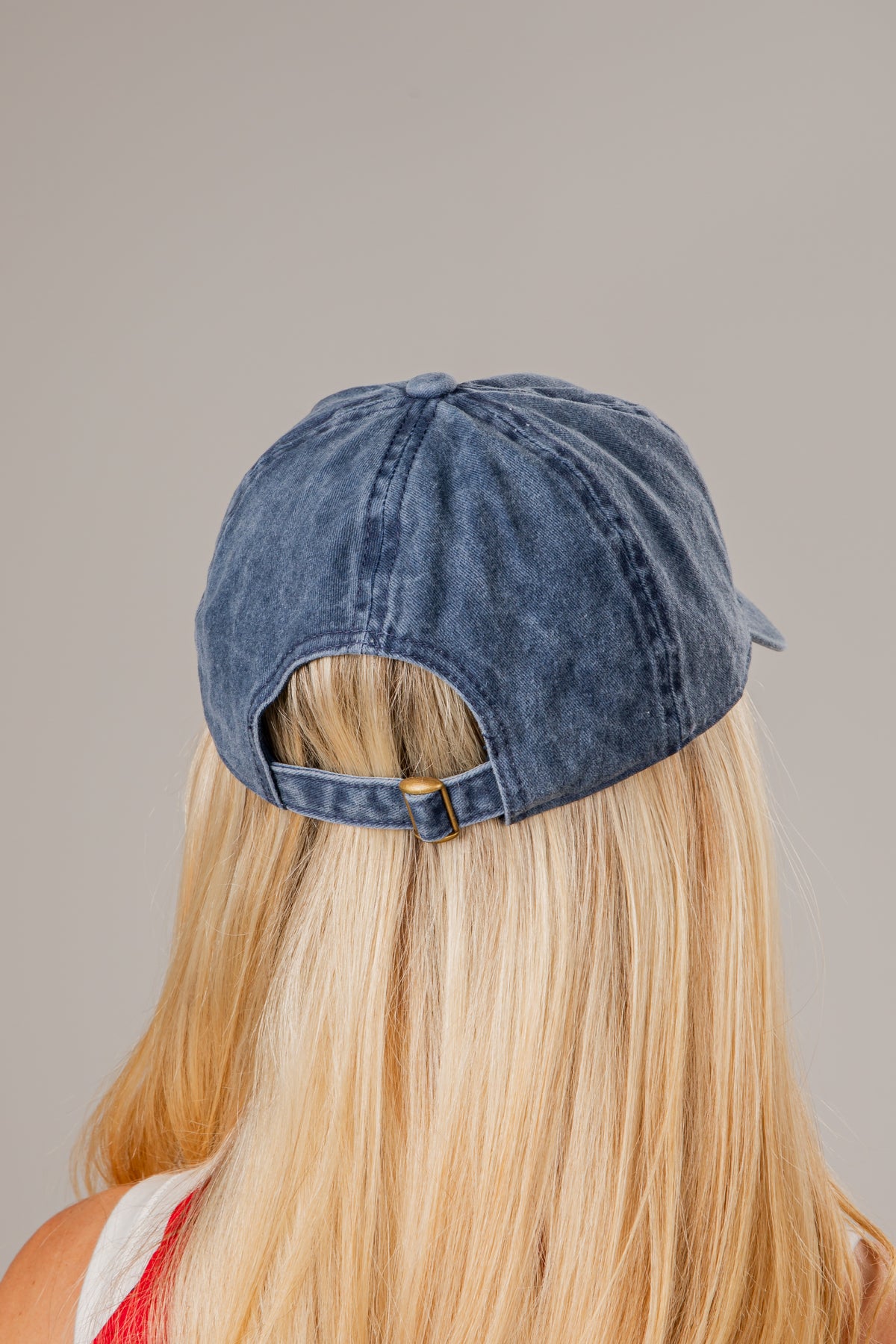 Blue denim cap worn by a person with blonde hair on a neutral background