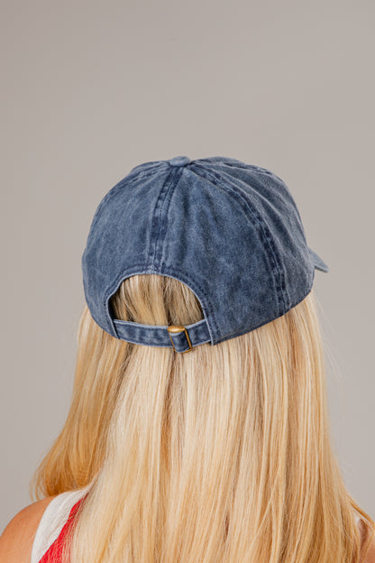 Blue denim cap worn by a person with blonde hair on a neutral background