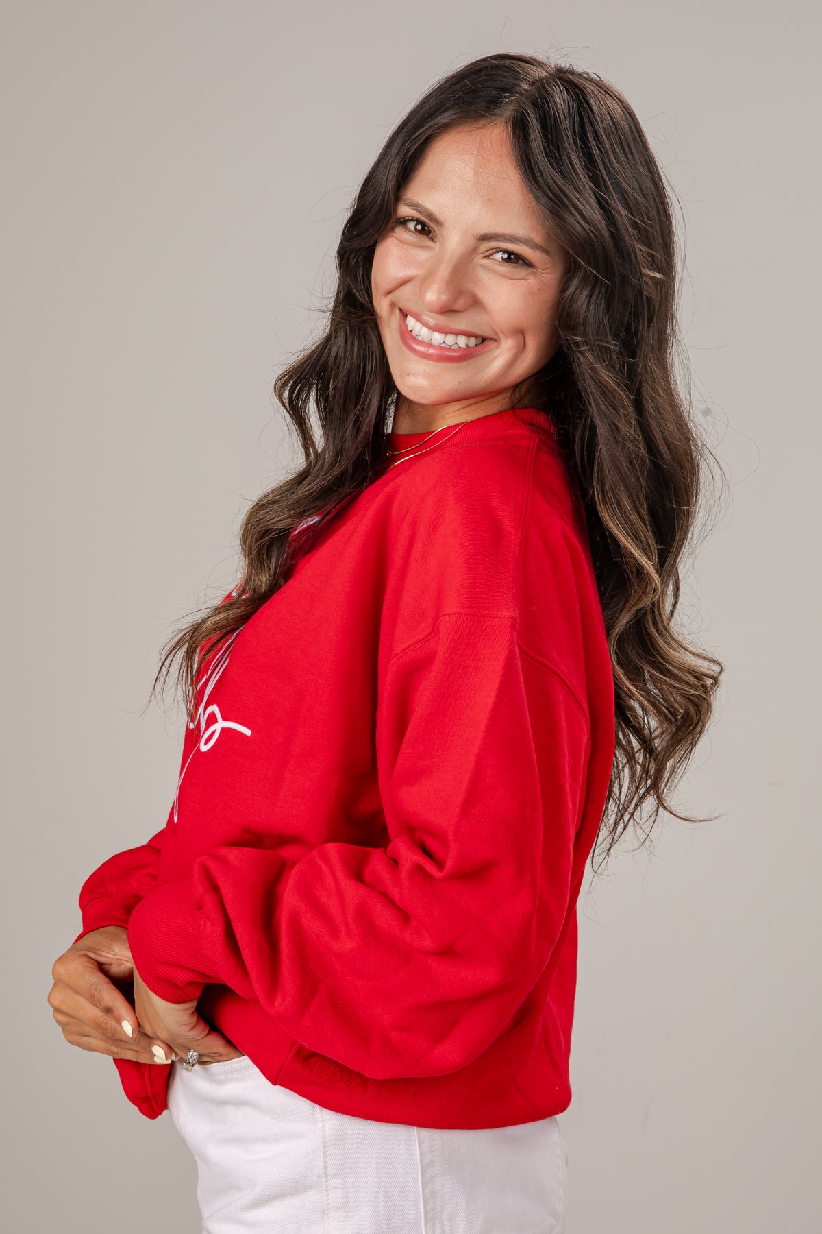 Woman wearing a red sweatshirt with a logo on a gray background