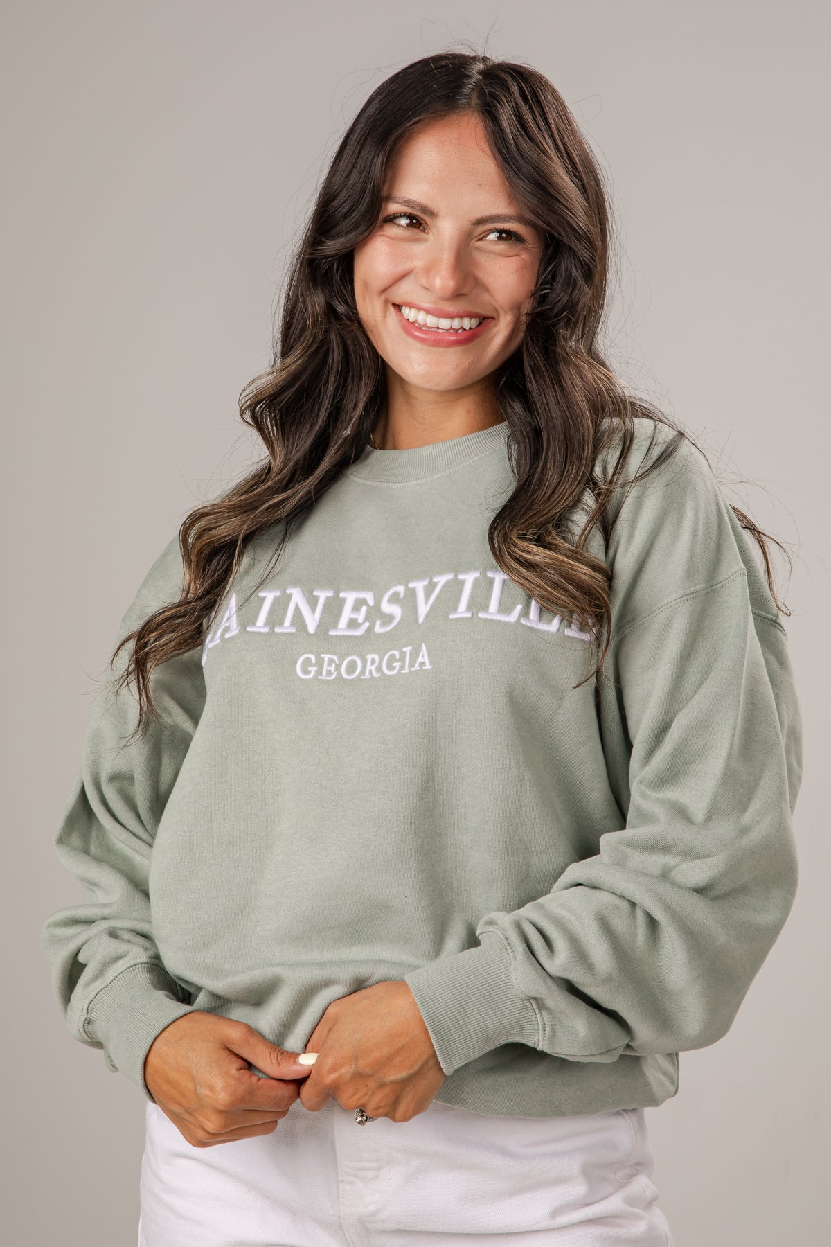 Woman wearing a light green sweatshirt with &